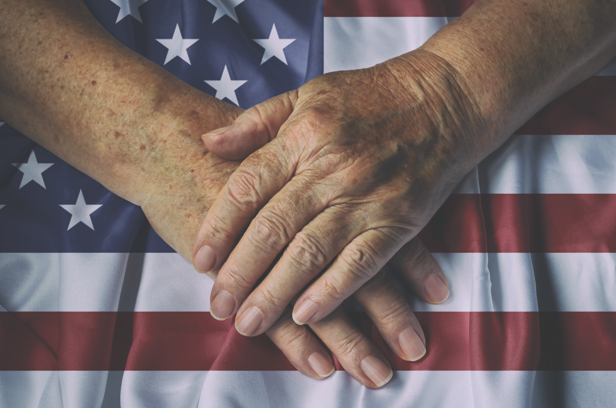 Old woman's hands with American flag, top view.
