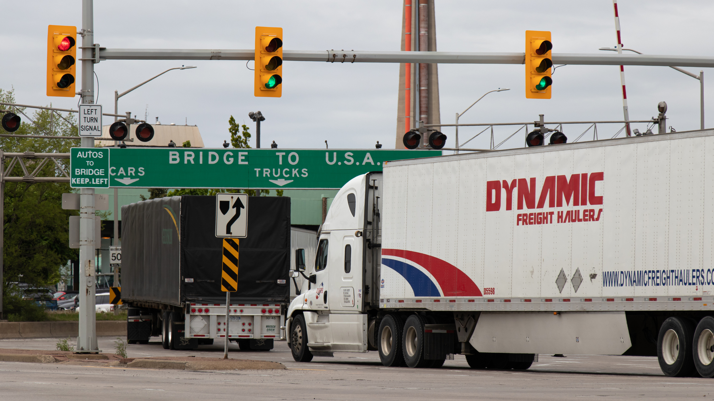 Transport trucks pass under a "Bridge To USA" at the entrance to the Ambassador Bridge, US-Canada border crossing. (Windsor, Ontario)